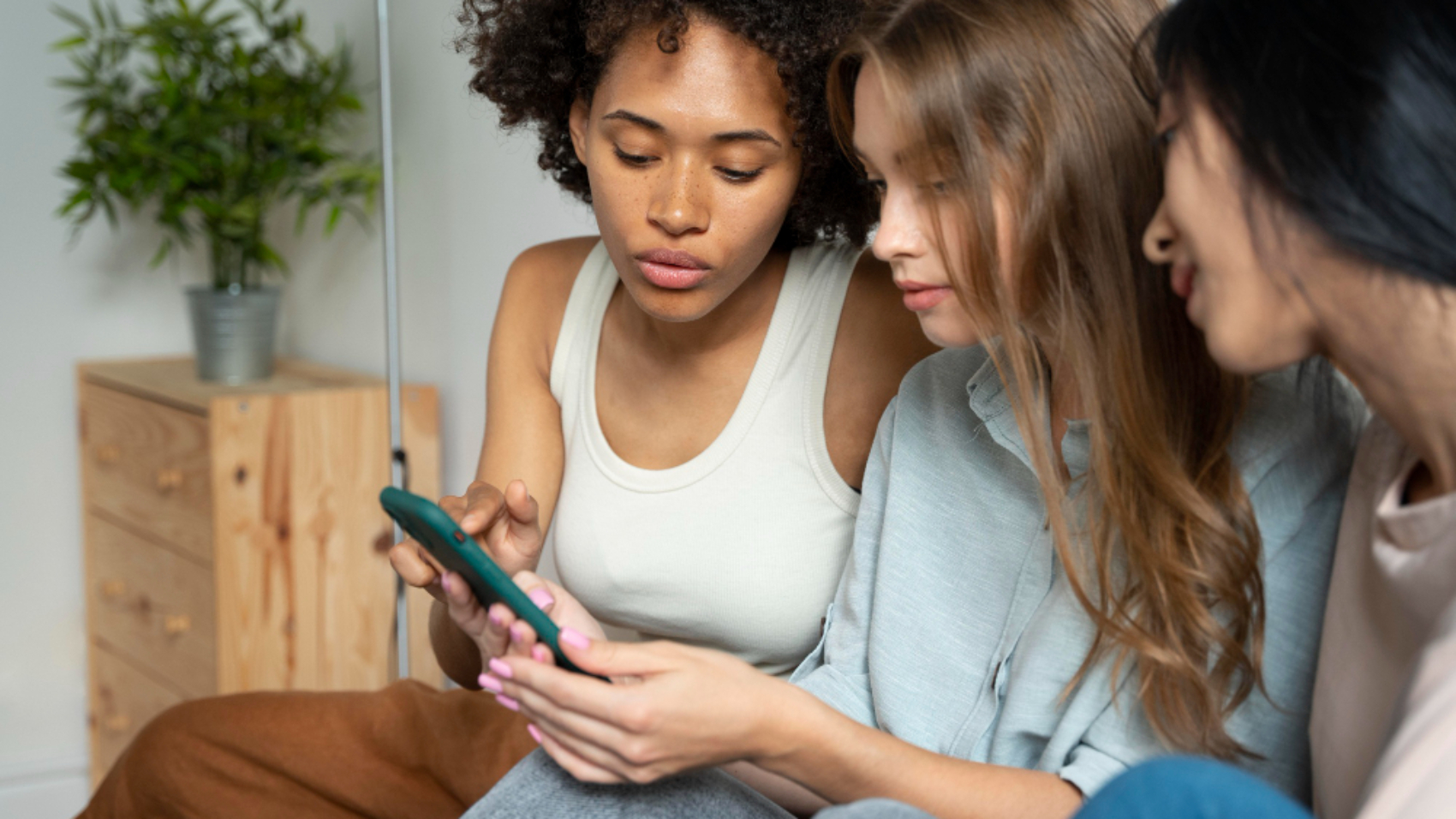 jovens colaboradoras usando um smartphone para acessar conteúdos de comunicação interna