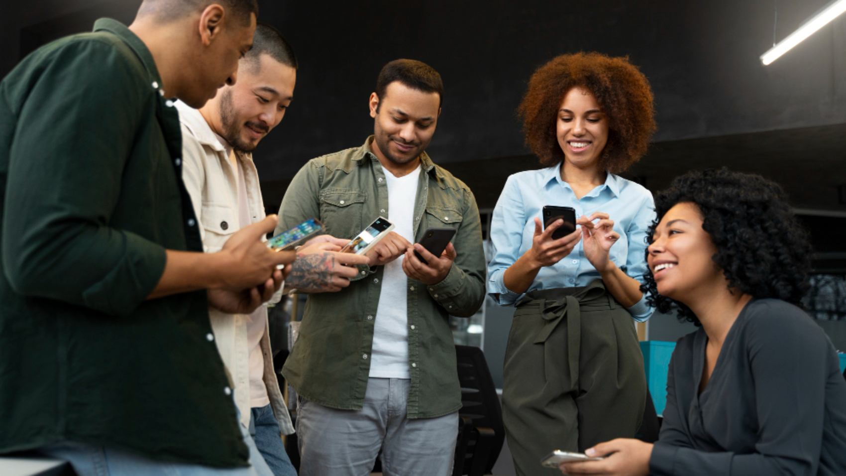 Equipe utilizando smartphones para trocar informações e fortalecer a comunicação interna durante processo de integração organizacional.