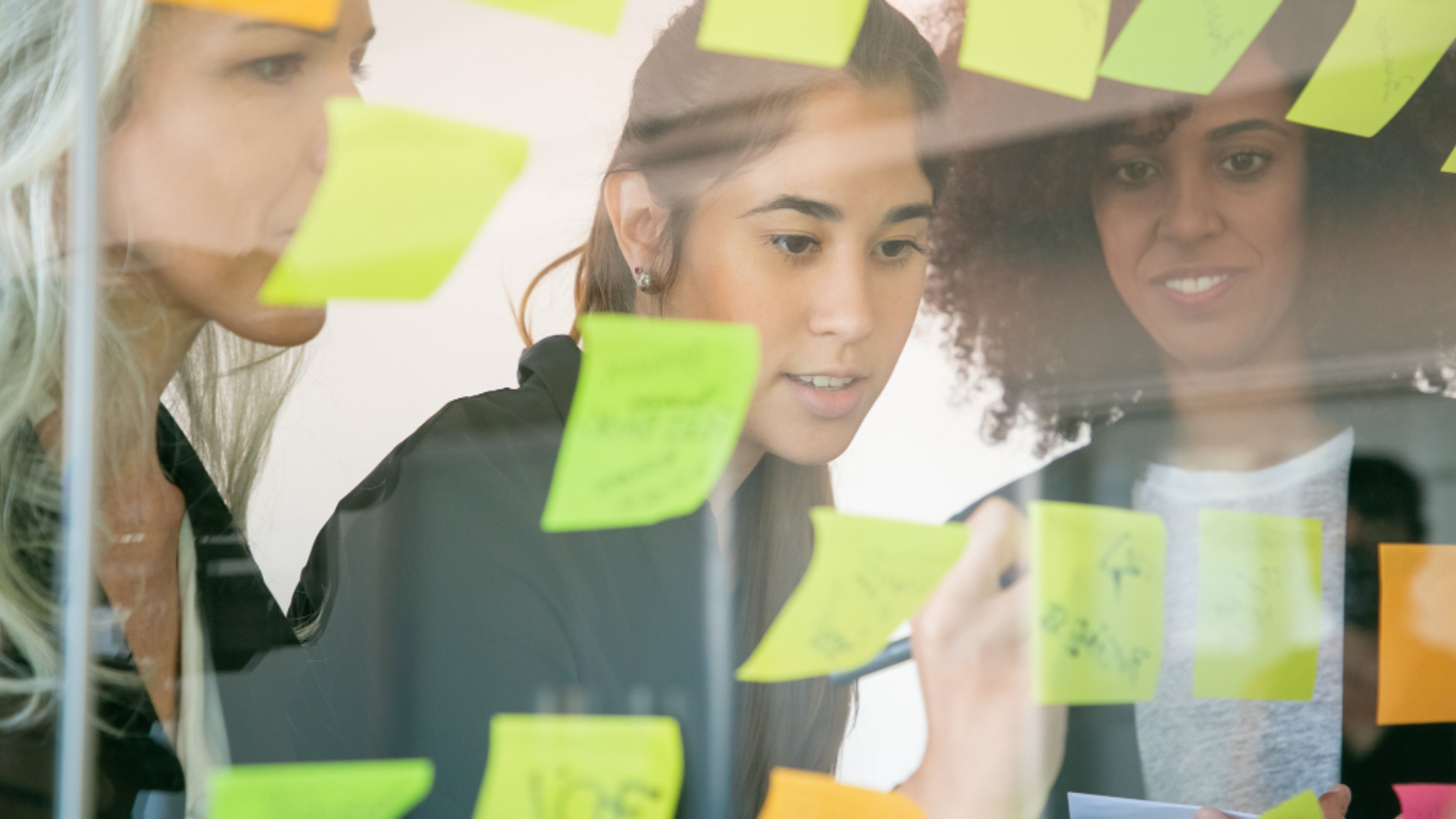 equipe planejando ações de employer branding com notas adesivas em painel de vidro