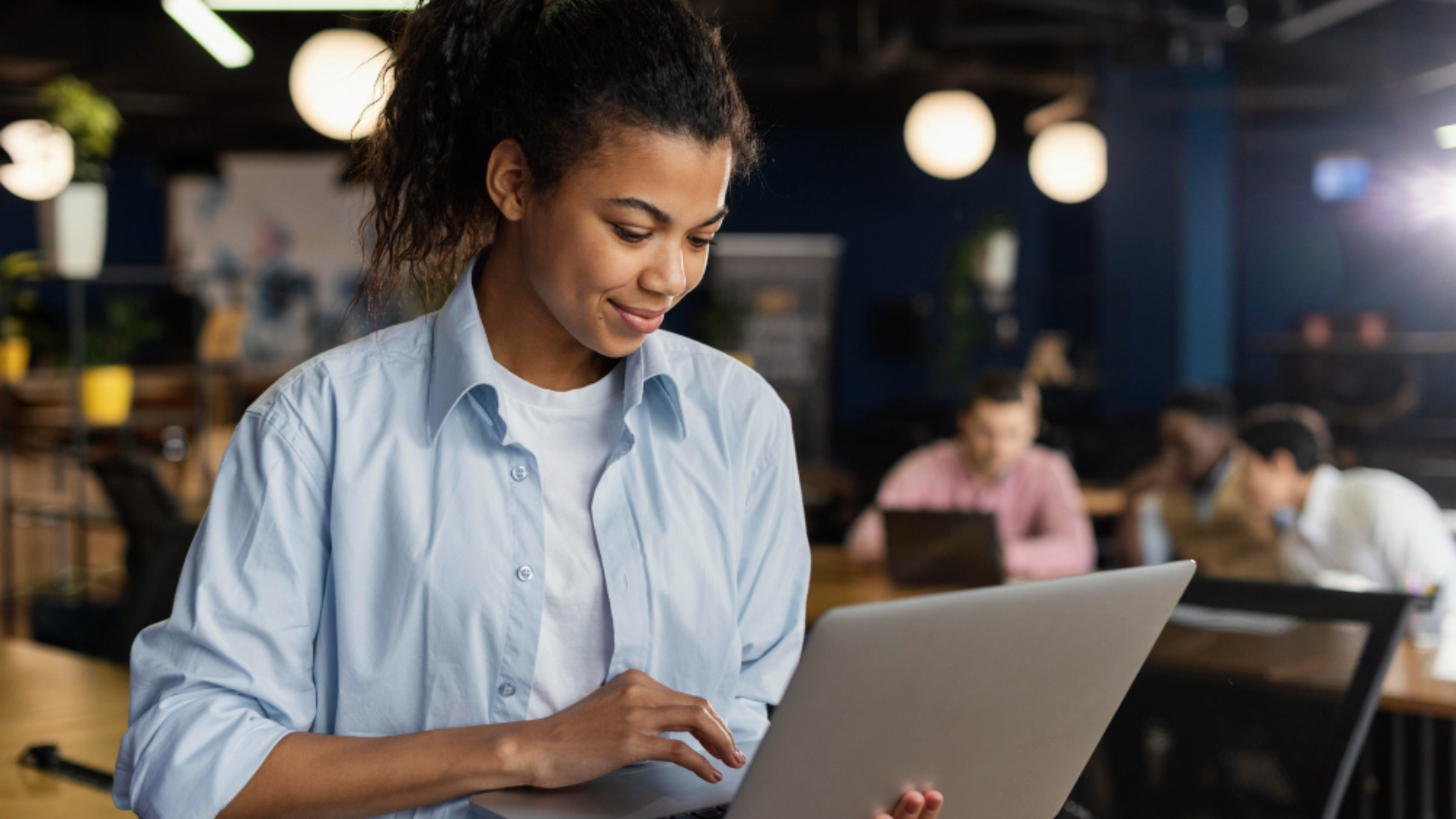 Colaboradora utilizando um notebook em um ambiente corporativo enquanto acessa uma plataforma de comunicação interna, representando a integração de equipes sem e-mail corporativo.