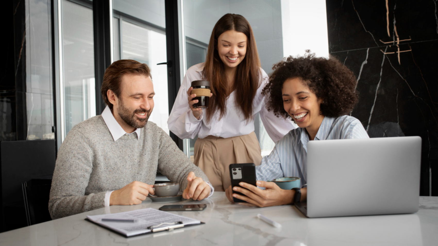 Equipe de vendas reunida em um ambiente corporativo consultando informações em smartphones e notebook, representando alinhamento, colaboração e comunicação interna entre vendedores.